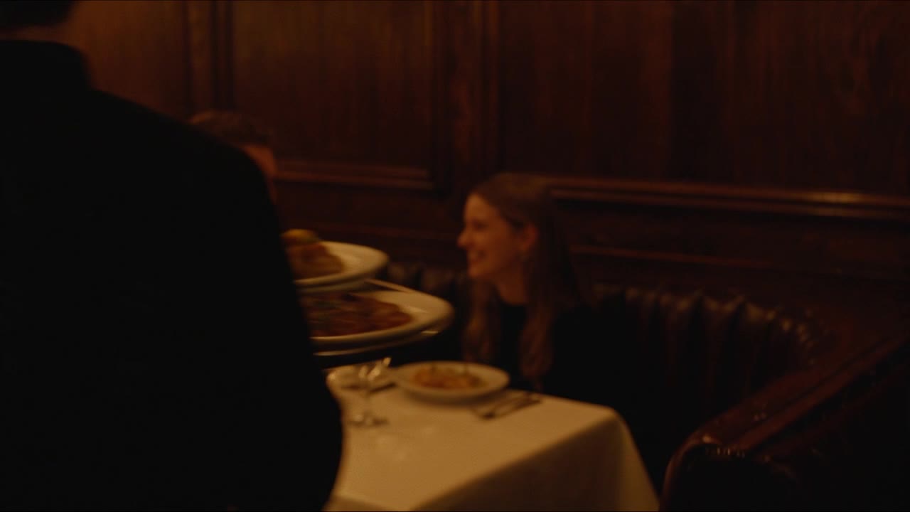 A guest smiling at her table as plates arrive