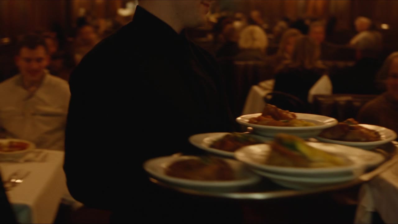 A server carrying plates through a full dining room